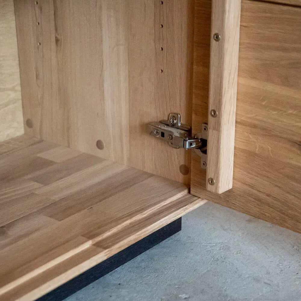Detailansicht einer Holz-Kommode, Türscharnier aus Metall, hochwertiges Massivholzmöbel.
