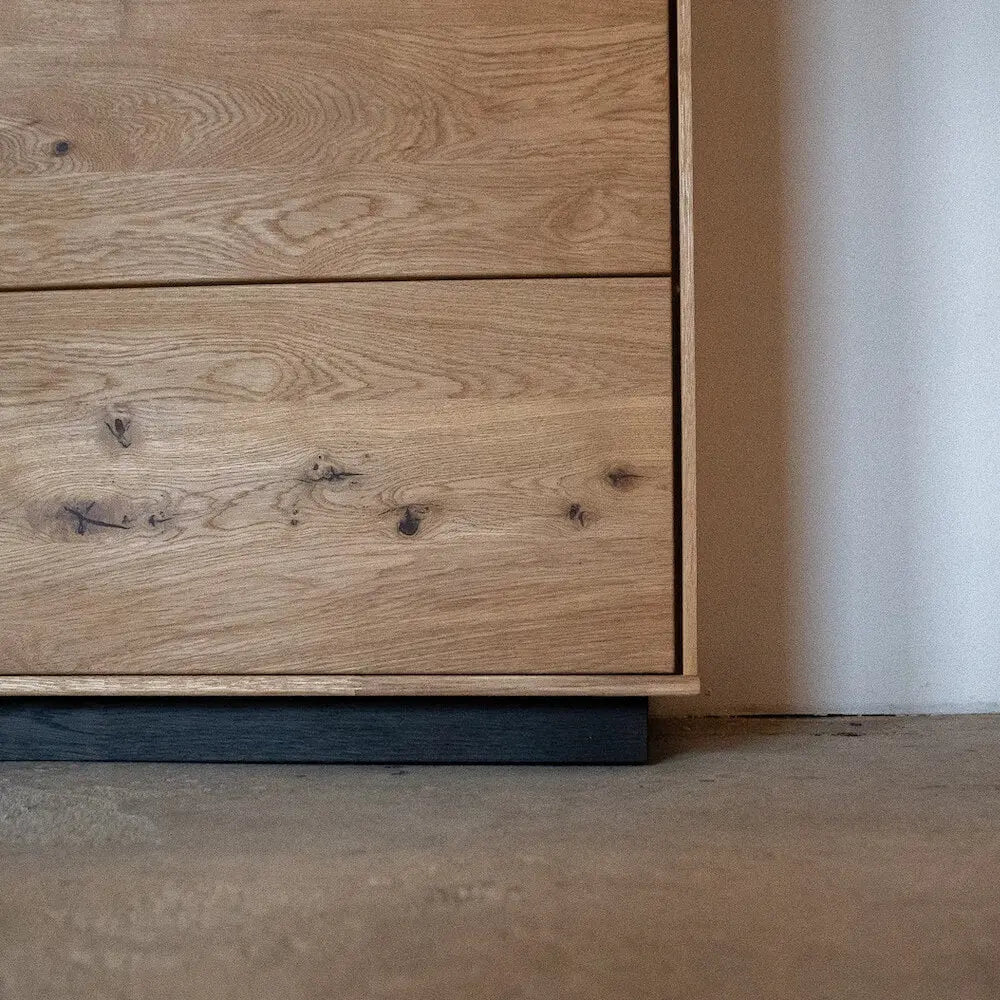 Detailansicht einer Kommode aus Eichenholz, schwarze Basis, modernes Design für Schlafzimmer.