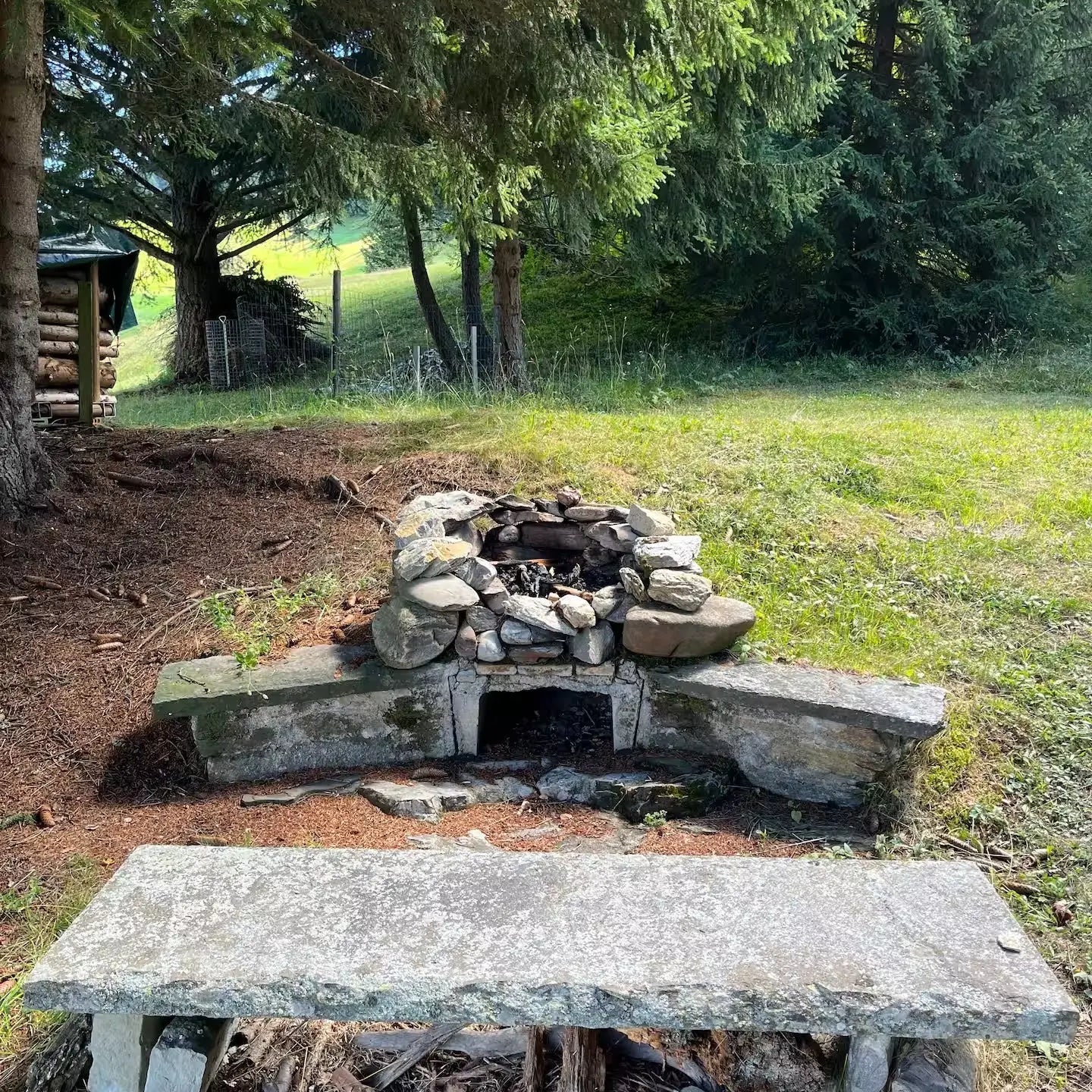 Feuerstelle aus Naturstein mit Steinbank im Wald. Naturverbundenes Outdoor-Kochen in der Natur.
