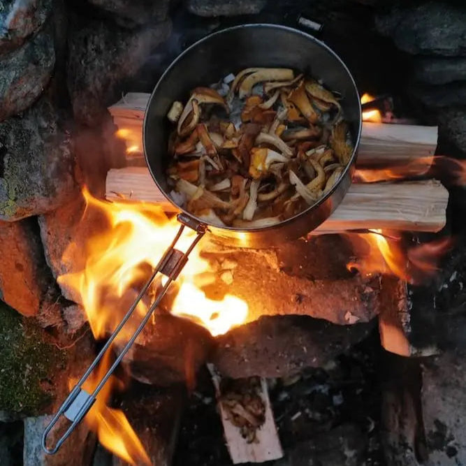 Frische Pfifferlinge braten in einer Pfanne über offenem Feuer – Wildküche mit Woodcuisine in den Schweizer Bergen.