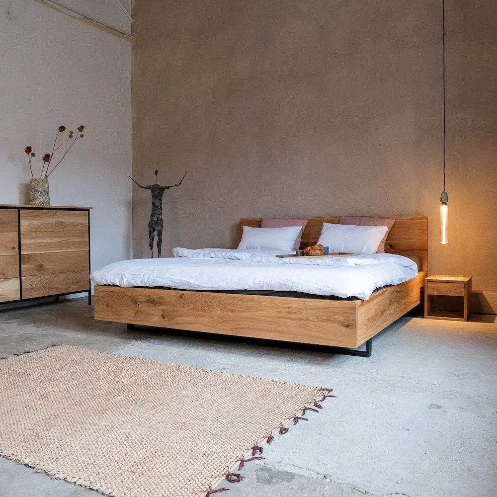 Massivholzbett mit Kufengestell aus Eiche, Industrial-Stil, weiße Bettwäsche, rustikale Loft-Ästhetik.