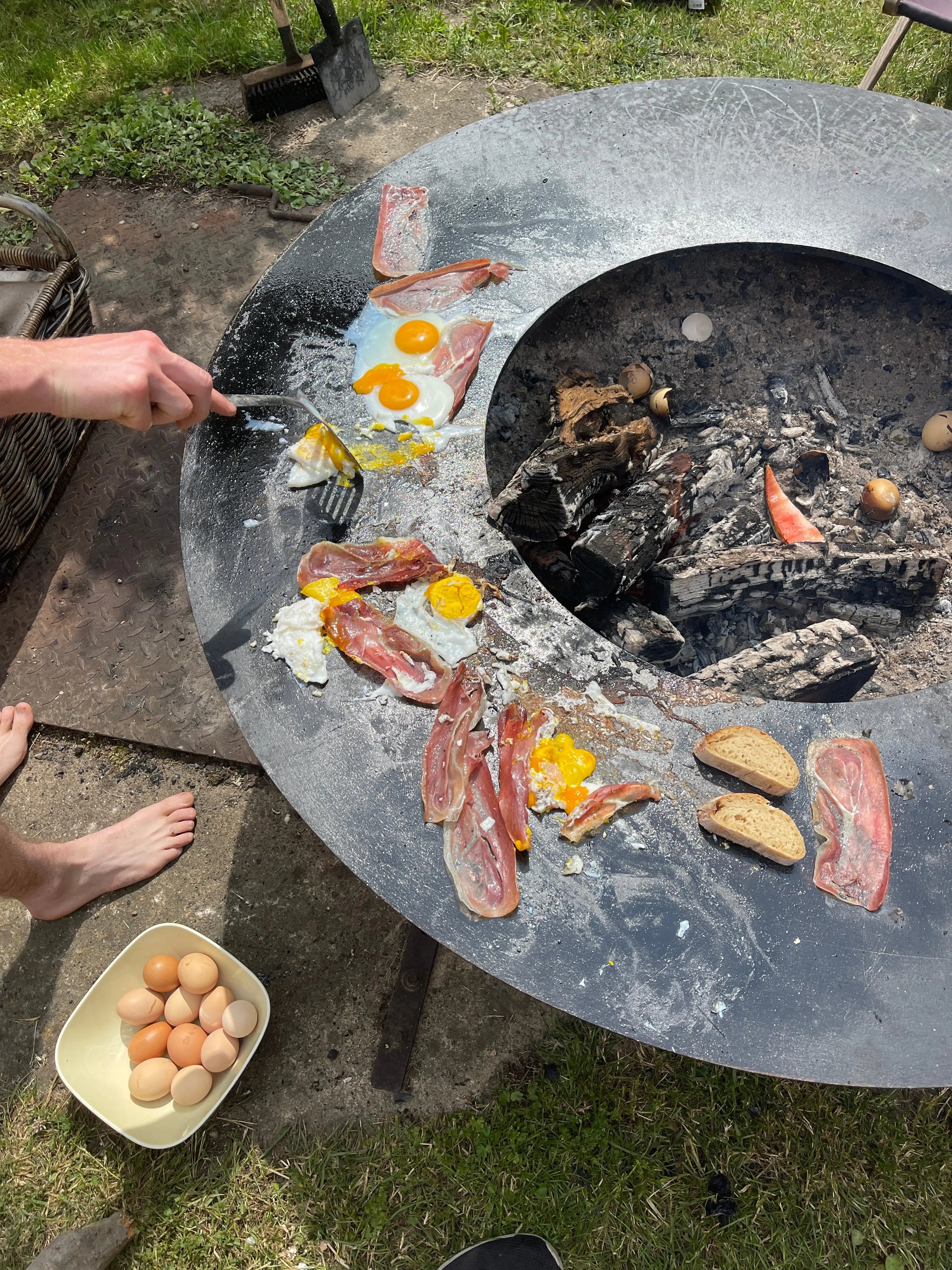 Woodcuisine by Woodboom – Frühstück mit Eiern, Speck & Brot auf Feuerring über offenem Feuer zubereitet.