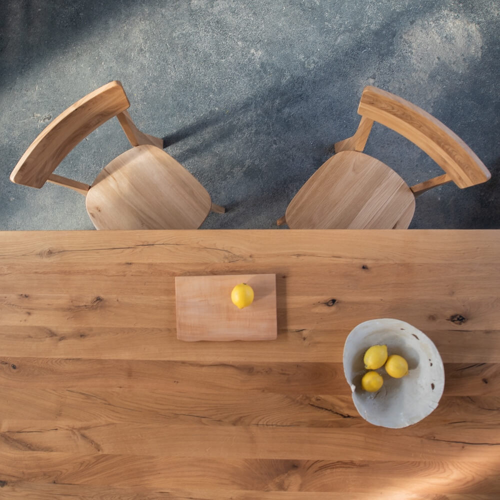 Zwei Esszimmerstühle LUMA aus Eiche an Massivholztisch mit Zitronen – zeitloses Möbeldesign von Woodboom