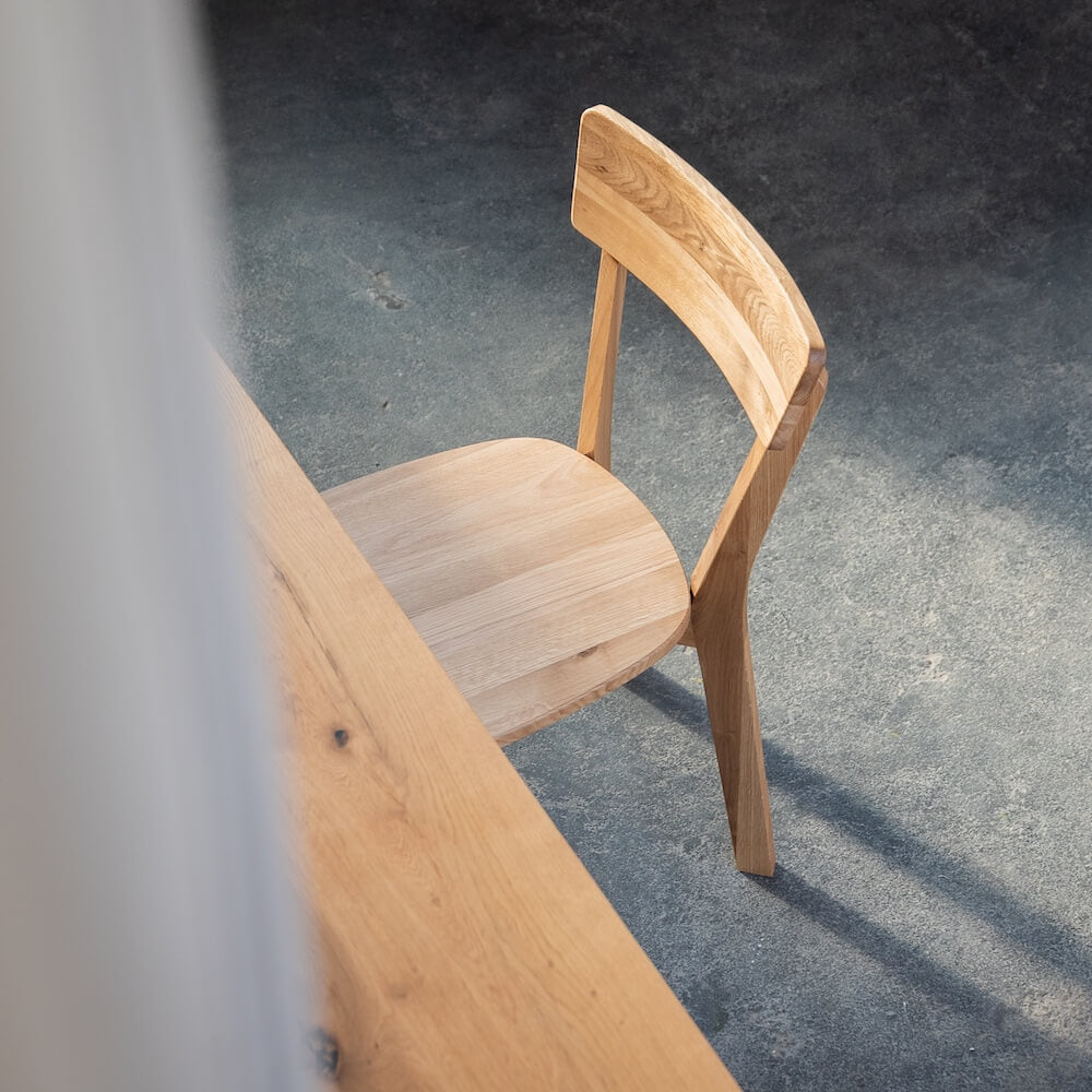 sszimmerstuhl aus Eiche an konischem Massivholztisch in hellem Raum mit Boden aus Sichtbeton