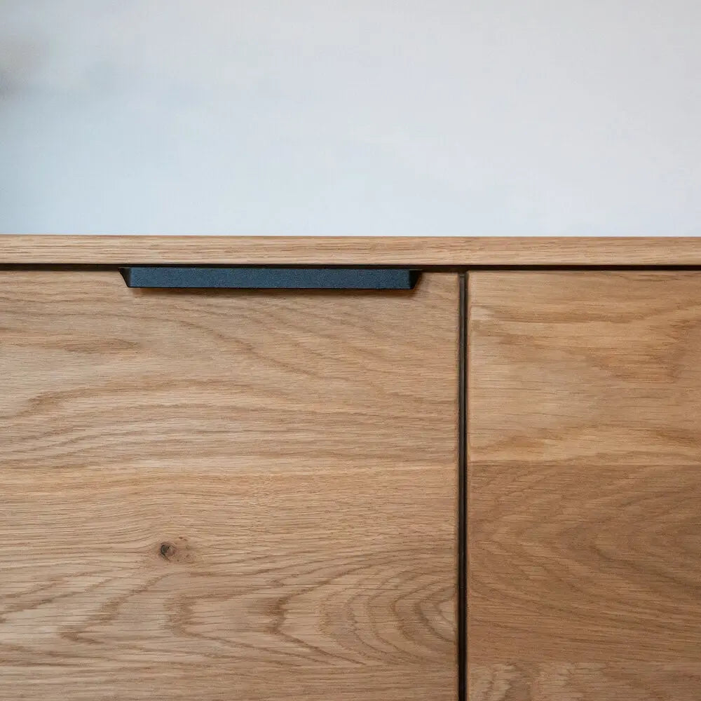Detailansicht einer Eichenholz-Kommode mit schwarzem Griff, minimalistisches Design.
