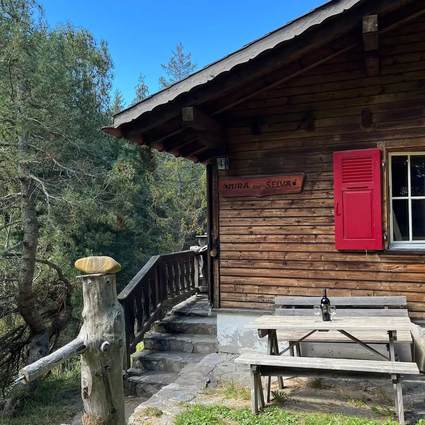 Woodcuisine Berghütte in der Schweiz – rustikale Holzhütte mit rotem Fensterladen & Holztisch